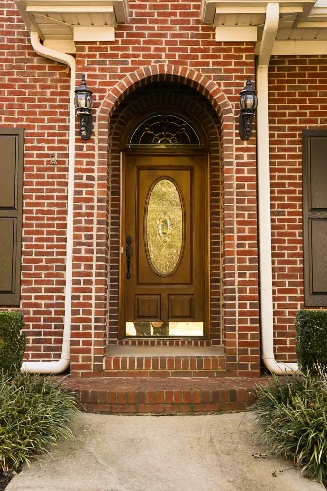 The bare arched brick entry before the holiday installation: two empty stone urns beside the front door