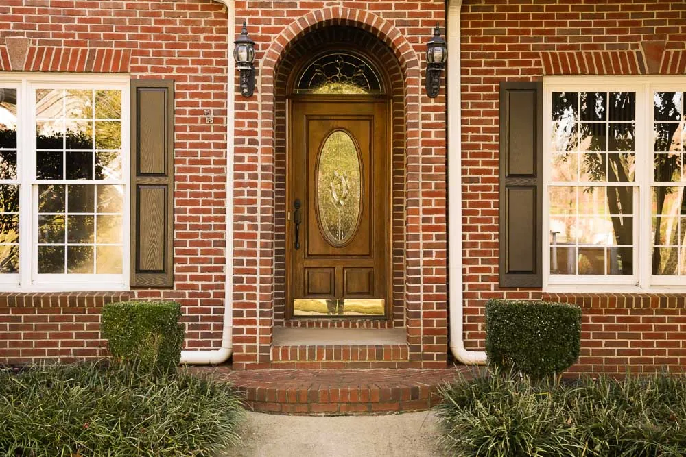 Holiday urn with cypress and magnolia against brick