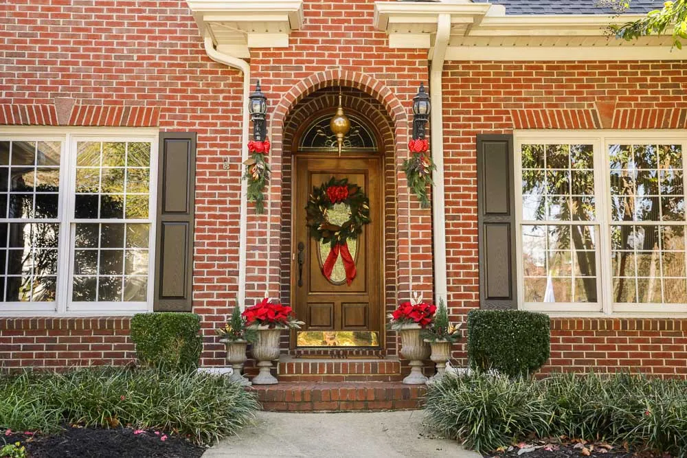 Holiday installation across an arched brick entry: urns, garland and greenery working as one composition
